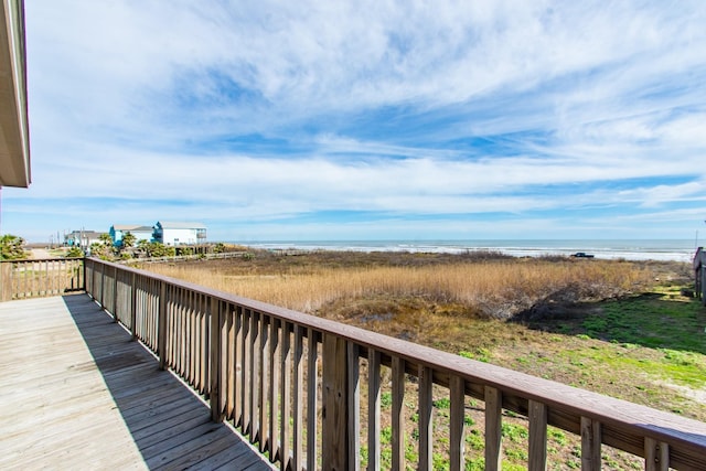 wooden deck with a water view and a beach view