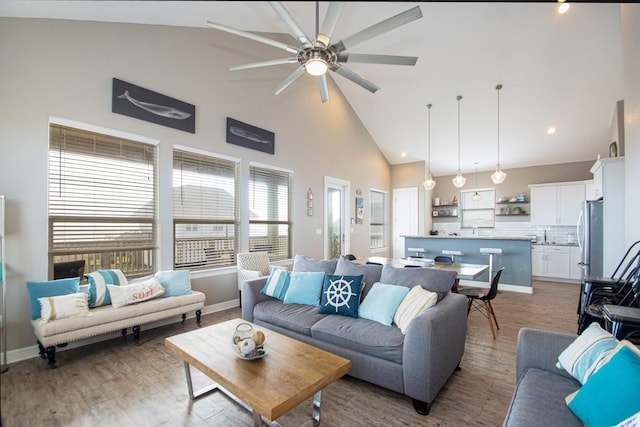 living room with high vaulted ceiling, ceiling fan, and light hardwood / wood-style flooring