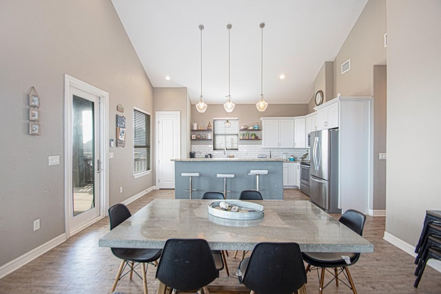 dining room with light wood-type flooring, high vaulted ceiling, and sink