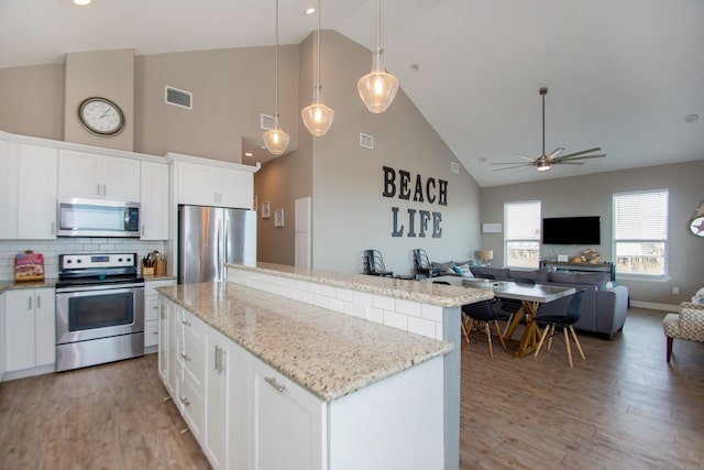 kitchen with white cabinetry, stainless steel appliances, a center island, decorative light fixtures, and hardwood / wood-style floors