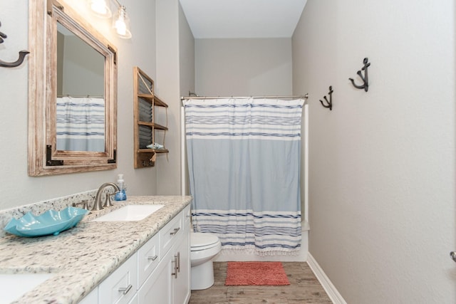 bathroom with toilet, vanity, and wood-type flooring