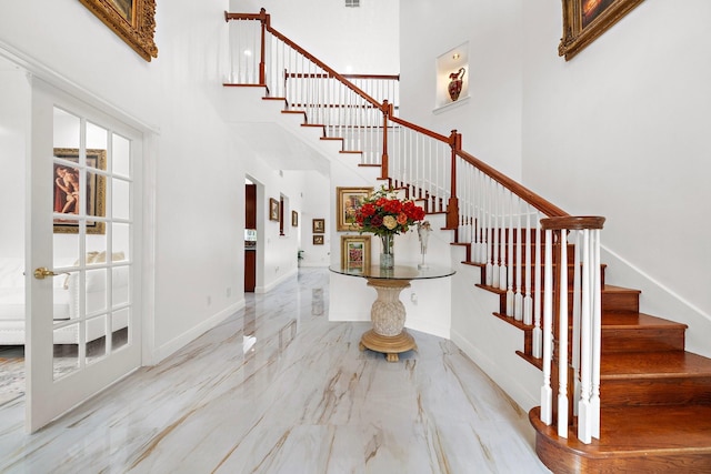 entrance foyer with visible vents, baseboards, stairway, marble finish floor, and a high ceiling