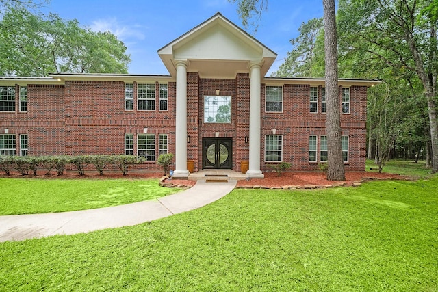 greek revival house featuring a front yard and brick siding