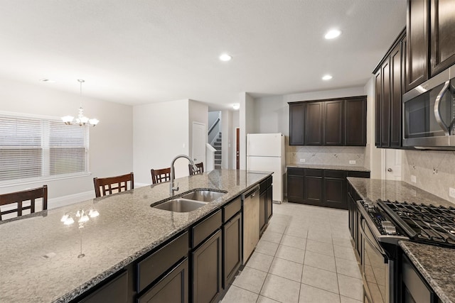 kitchen with stainless steel appliances, decorative light fixtures, light stone countertops, sink, and dark brown cabinets