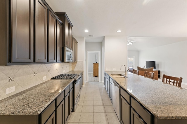 kitchen featuring tasteful backsplash, stainless steel appliances, light stone countertops, light tile patterned floors, and sink