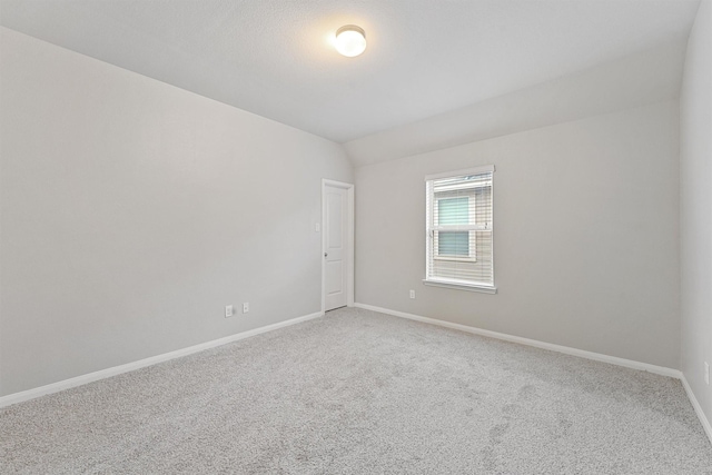 spare room featuring carpet floors and lofted ceiling