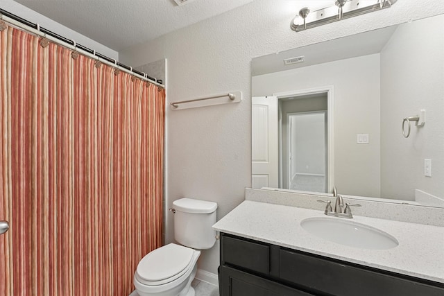 bathroom with vanity, toilet, and a textured ceiling