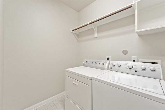 laundry area with independent washer and dryer and light tile patterned floors