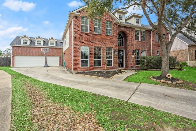 traditional-style home with a garage, brick siding, concrete driveway, and a front yard