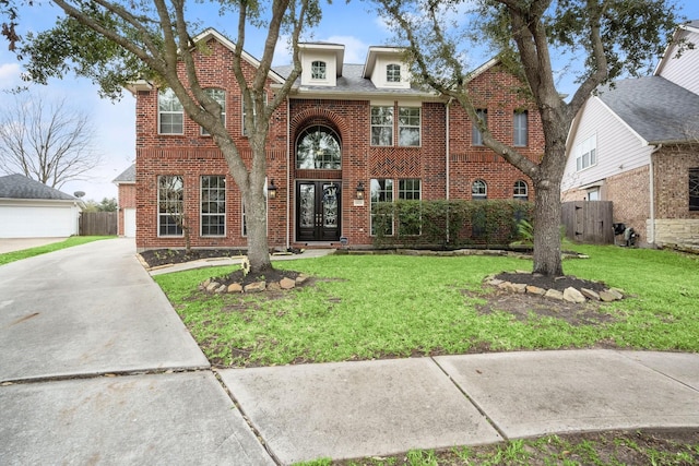 view of front of home featuring french doors, brick siding, fence, and a front lawn