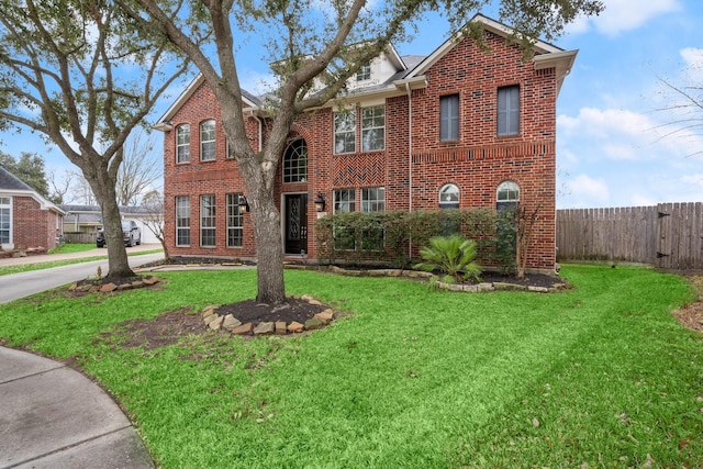 view of front of home with brick siding, a front lawn, and fence