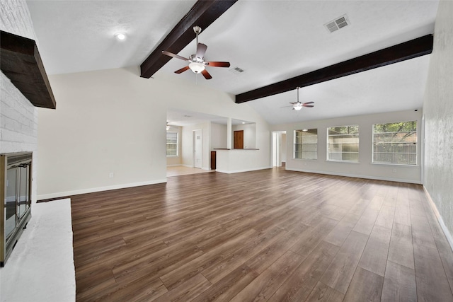 unfurnished living room with lofted ceiling with beams, visible vents, wood finished floors, and a fireplace