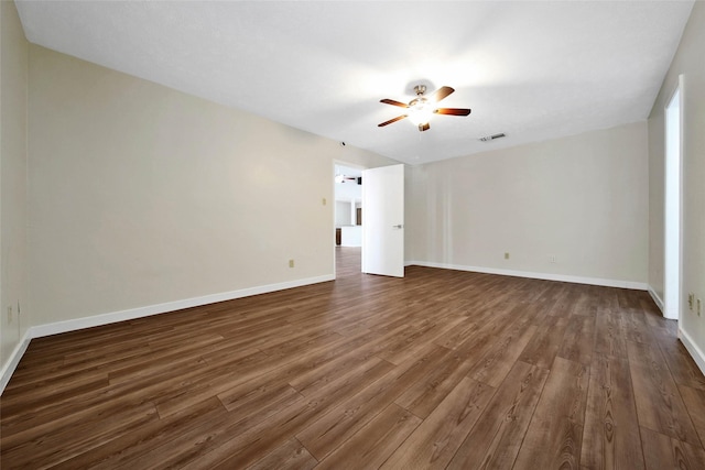 unfurnished room with dark wood-style floors, visible vents, ceiling fan, and baseboards