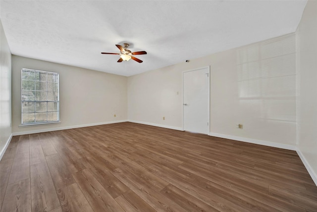 empty room with ceiling fan, baseboards, and wood finished floors