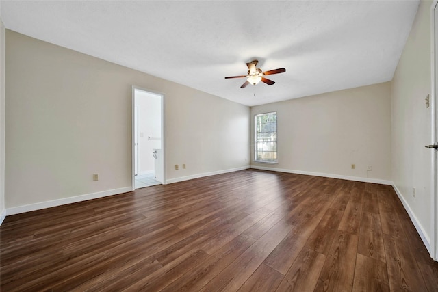 unfurnished room featuring dark wood finished floors, baseboards, and a ceiling fan