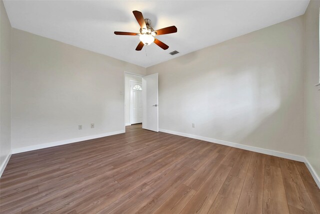 empty room featuring visible vents, ceiling fan, baseboards, and wood finished floors