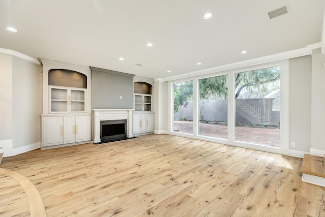 unfurnished living room with a healthy amount of sunlight, light hardwood / wood-style flooring, and crown molding