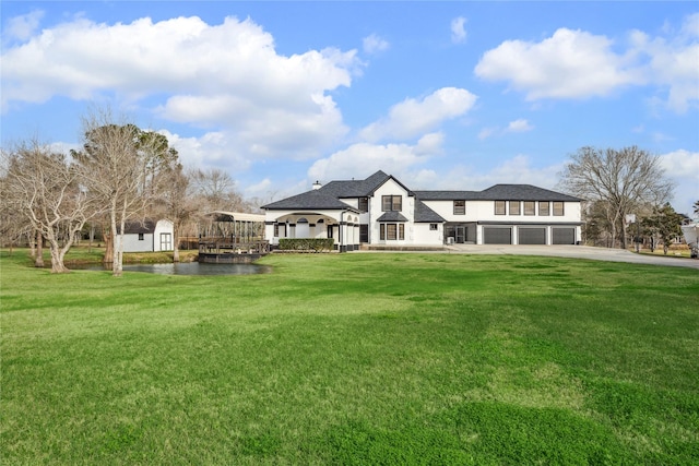 rear view of property featuring a lawn, a garage, and a gazebo