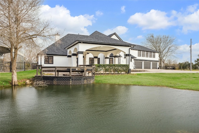 back of property featuring a lawn, a water view, and a garage