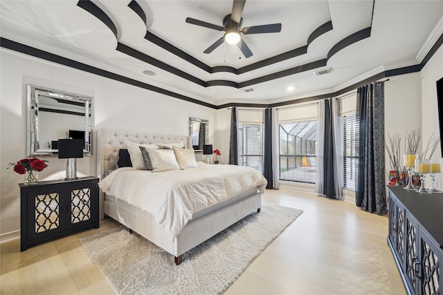 bedroom with a tray ceiling, light hardwood / wood-style flooring, and crown molding