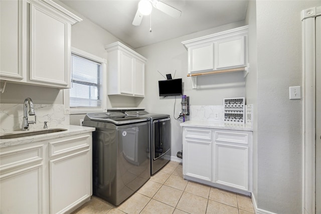 clothes washing area featuring cabinets, washing machine and clothes dryer, sink, ceiling fan, and light tile patterned floors