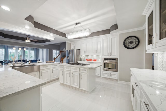 kitchen with a tray ceiling, stainless steel appliances, white cabinetry, and a center island