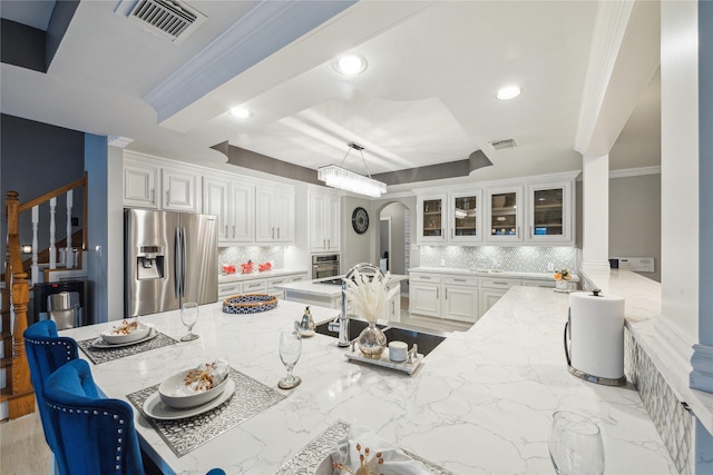 kitchen featuring appliances with stainless steel finishes, white cabinetry, light stone countertops, and kitchen peninsula