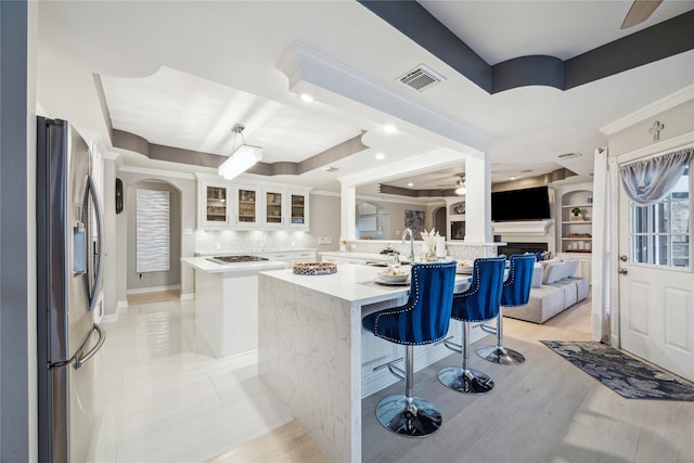 kitchen featuring stainless steel fridge with ice dispenser, white cabinets, a center island, and a raised ceiling