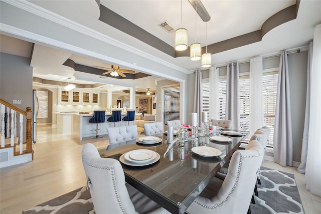 dining space with a tray ceiling, light hardwood / wood-style flooring, and ceiling fan