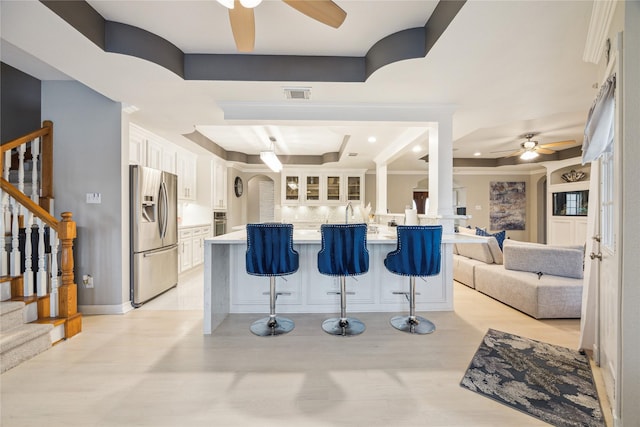 kitchen featuring a kitchen bar, stainless steel appliances, kitchen peninsula, white cabinets, and decorative backsplash