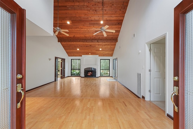 unfurnished living room with a lit fireplace, visible vents, high vaulted ceiling, and light wood-style flooring