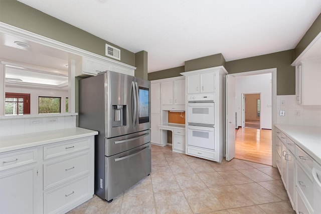 kitchen featuring tasteful backsplash, stainless steel fridge, visible vents, light countertops, and double oven