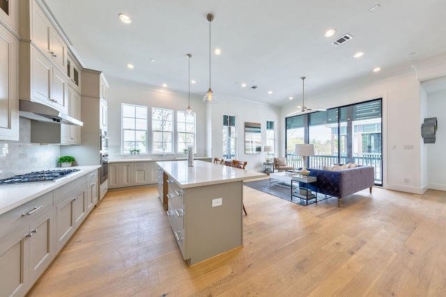 kitchen featuring a kitchen bar, backsplash, pendant lighting, a kitchen island, and stainless steel gas cooktop