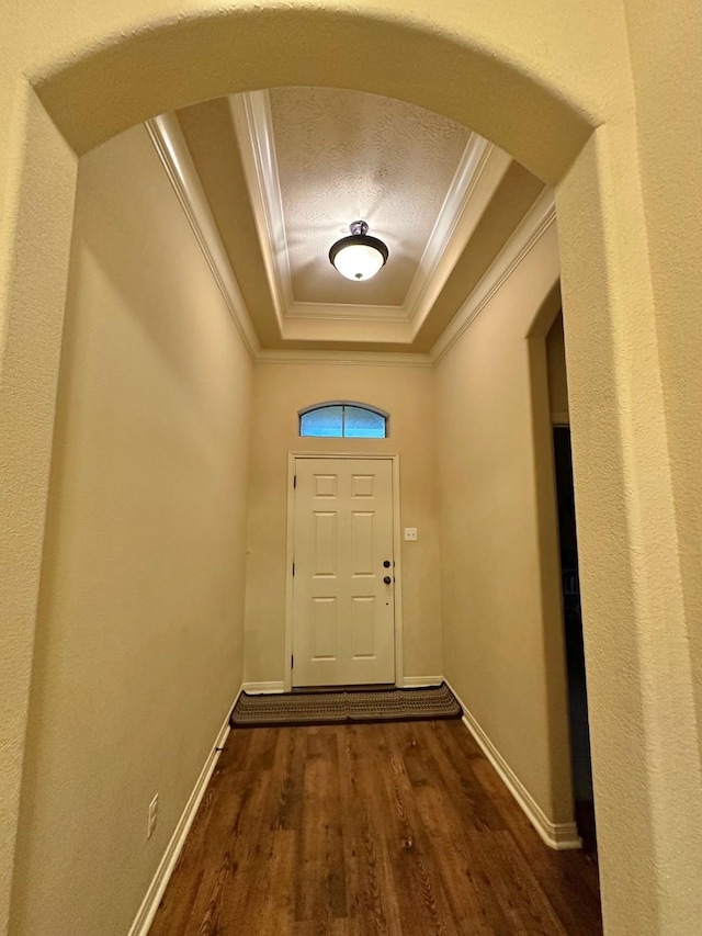 doorway to outside featuring a textured ceiling, a tray ceiling, dark wood-type flooring, and ornamental molding