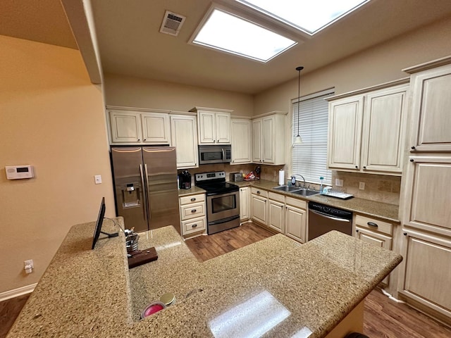 kitchen featuring sink, appliances with stainless steel finishes, light stone counters, and pendant lighting