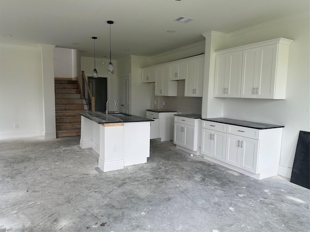 kitchen with sink, a center island with sink, white cabinets, and pendant lighting