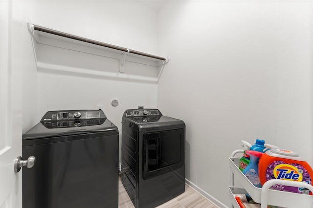 washroom with laundry area, baseboards, and washing machine and clothes dryer