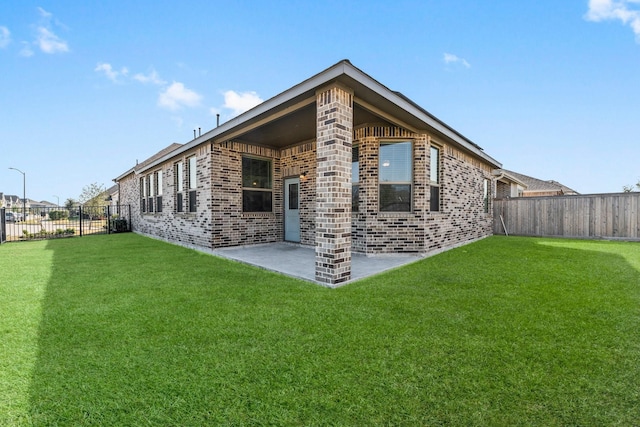 back of property with a patio area, brick siding, a yard, and a fenced backyard