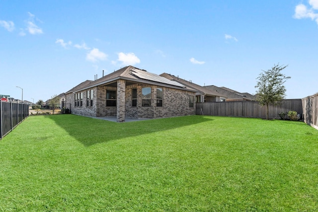 rear view of house with a patio area, a fenced backyard, brick siding, and a lawn