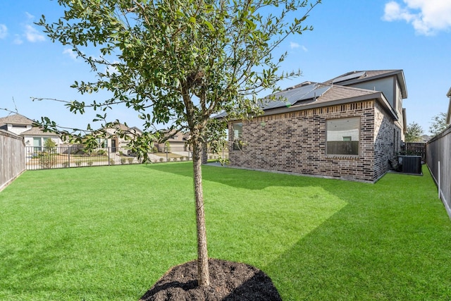 view of yard with a fenced backyard and central AC