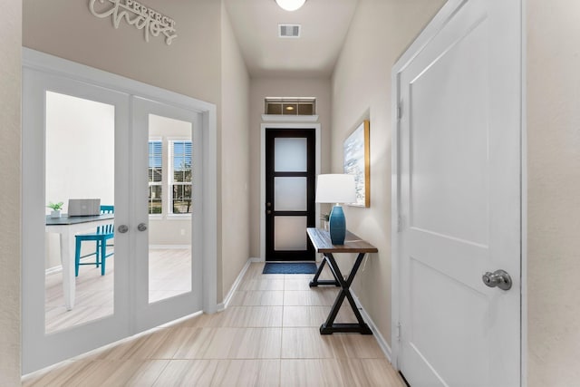 doorway to outside with light tile patterned floors, visible vents, baseboards, and french doors