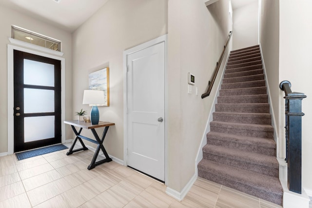 foyer entrance with stairs and baseboards