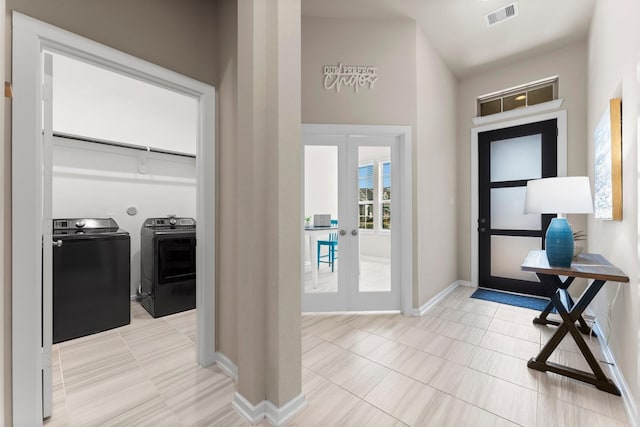 tiled entrance foyer featuring washing machine and dryer, french doors, visible vents, and baseboards