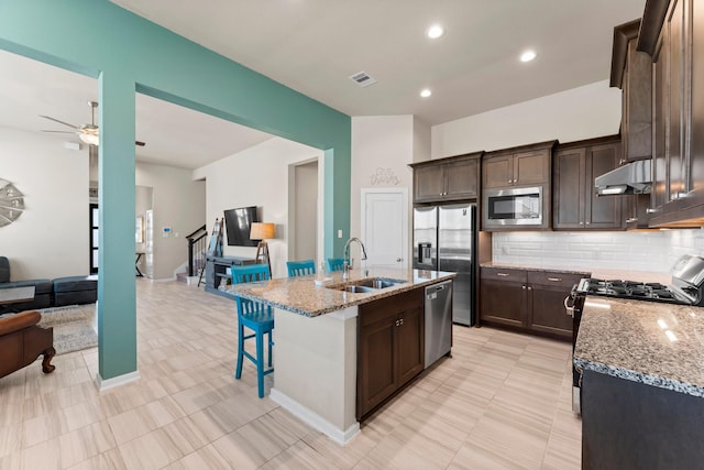 kitchen featuring visible vents, appliances with stainless steel finishes, a sink, an island with sink, and under cabinet range hood