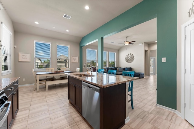 kitchen with visible vents, an island with sink, light stone counters, stainless steel dishwasher, and a sink