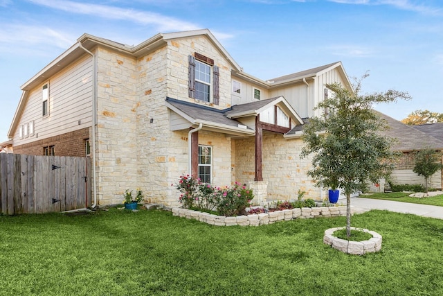 view of front of home with a front yard, stone siding, and fence