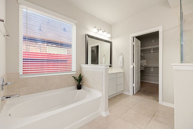 bathroom featuring a garden tub, vanity, baseboards, a spacious closet, and tile patterned floors