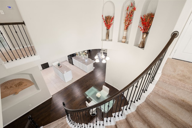 staircase featuring wood finished floors and an inviting chandelier