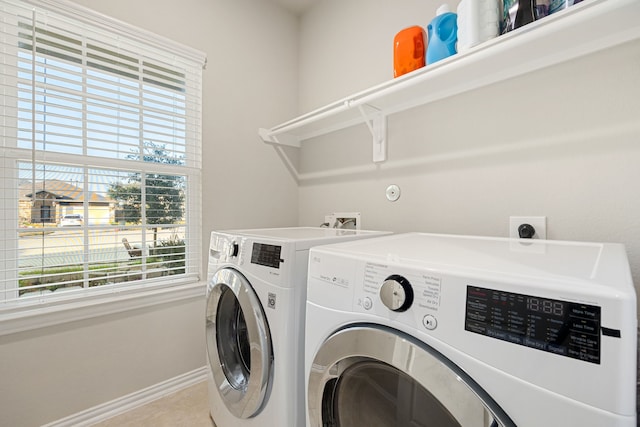 clothes washing area with laundry area, washing machine and dryer, and baseboards