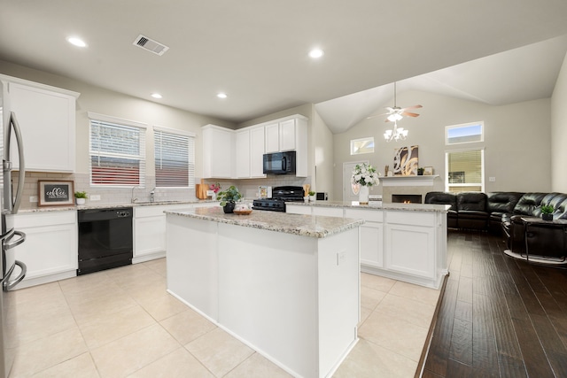 kitchen with visible vents, white cabinets, open floor plan, a center island, and black appliances